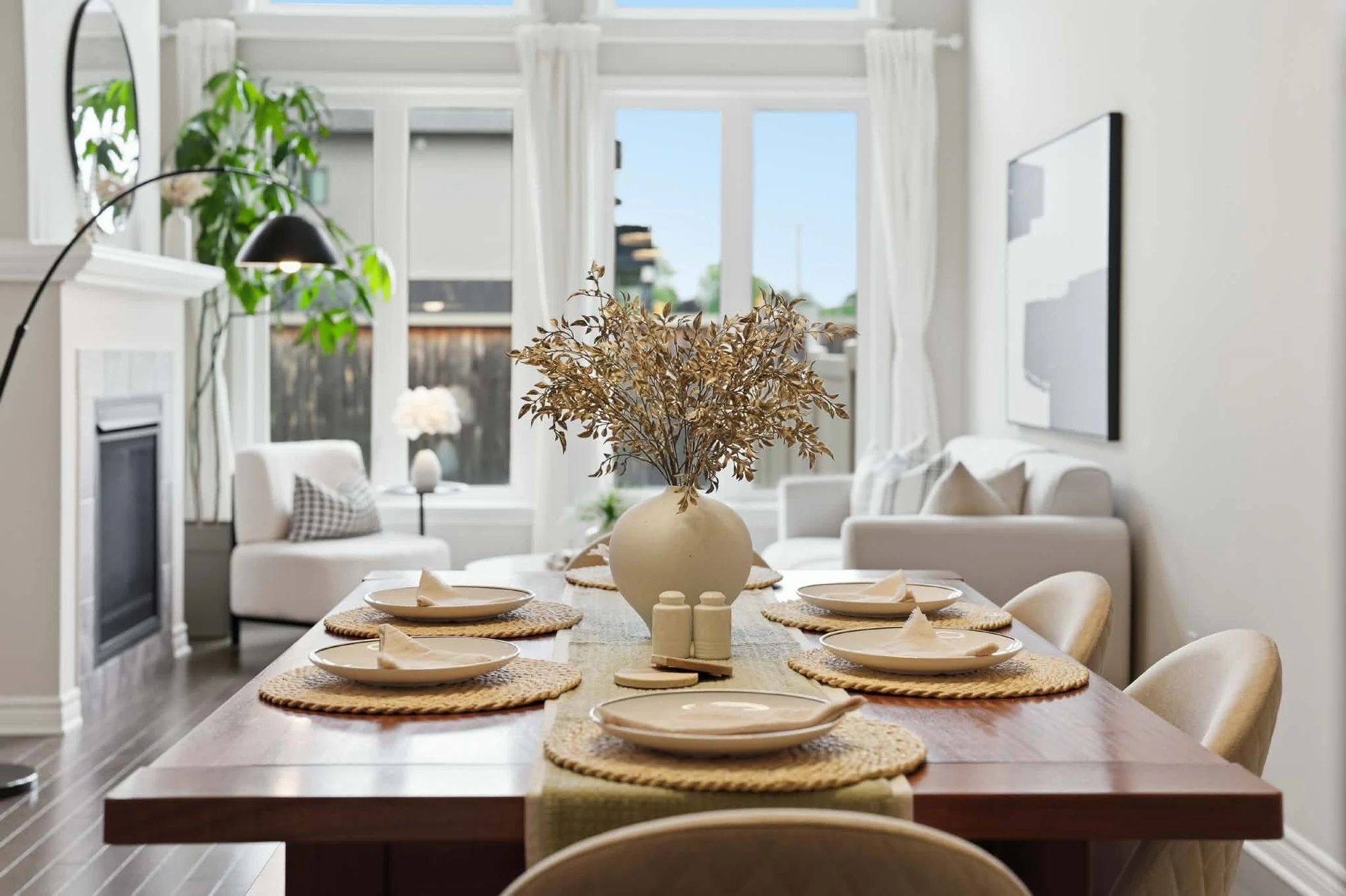Set dining table with woven placemats and cream chairs opening onto a bright living room