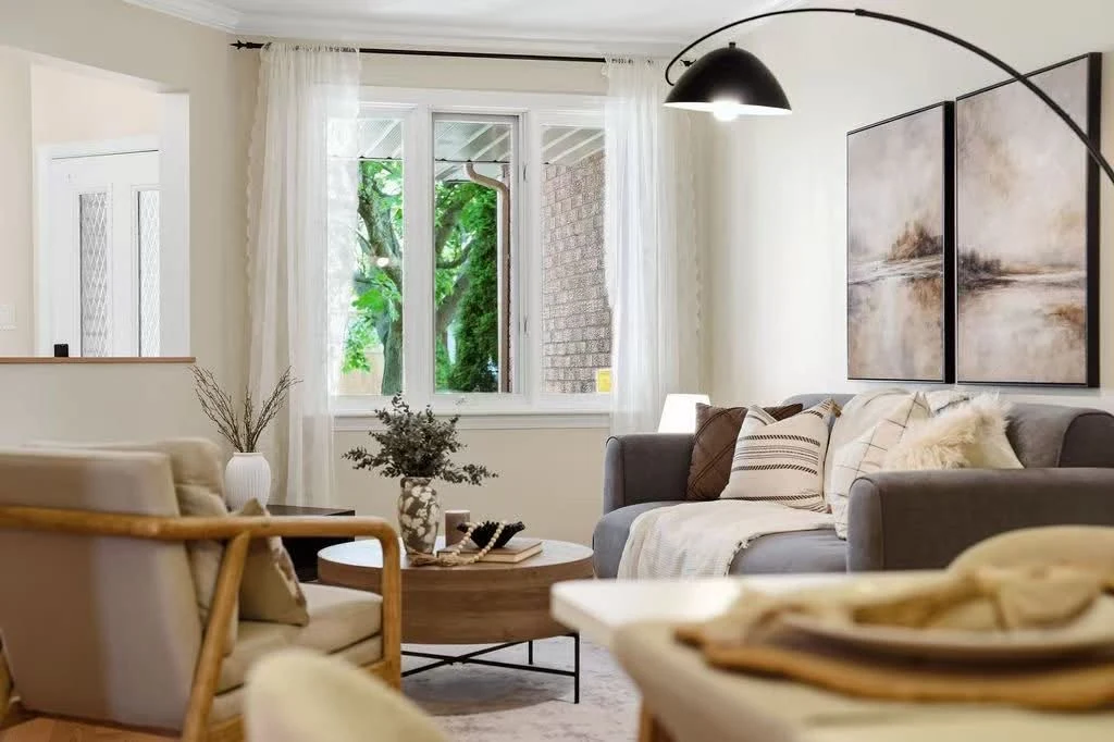 Bright living room with a grey sofa, wood armchair and paired landscape artwork